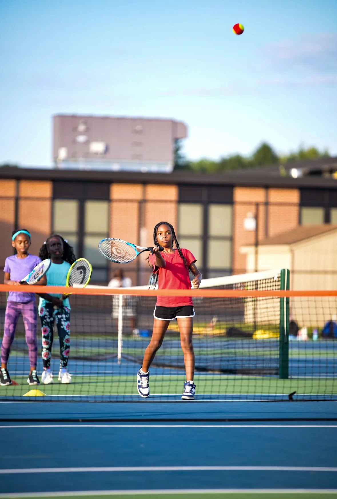 A girl playing tennis with her teammates nearby